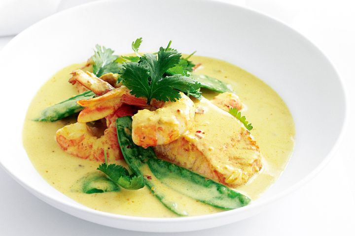 Cooking Fish Salmon and prawns in spicy coconut broth