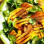 Barbecued pumpkin wedges on spinach salad